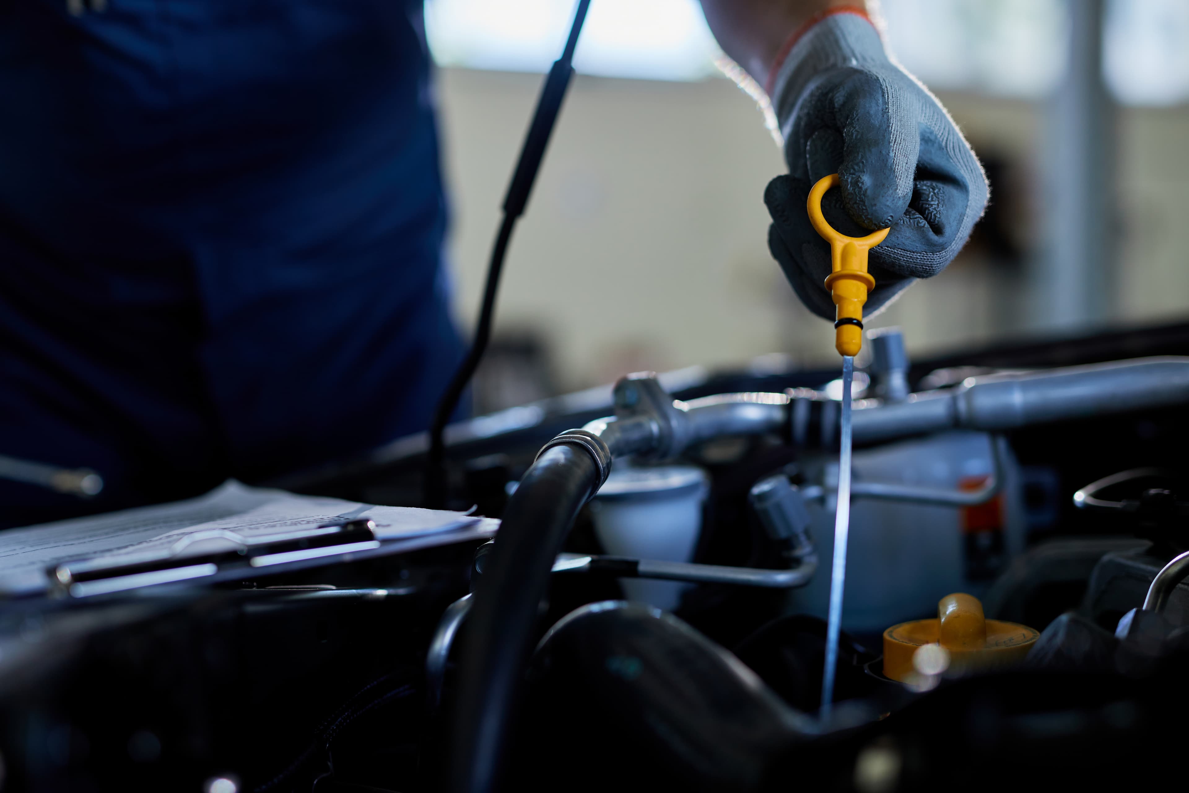 Mechanic checking engine oil level with a dipstick during vehicle maintenance
