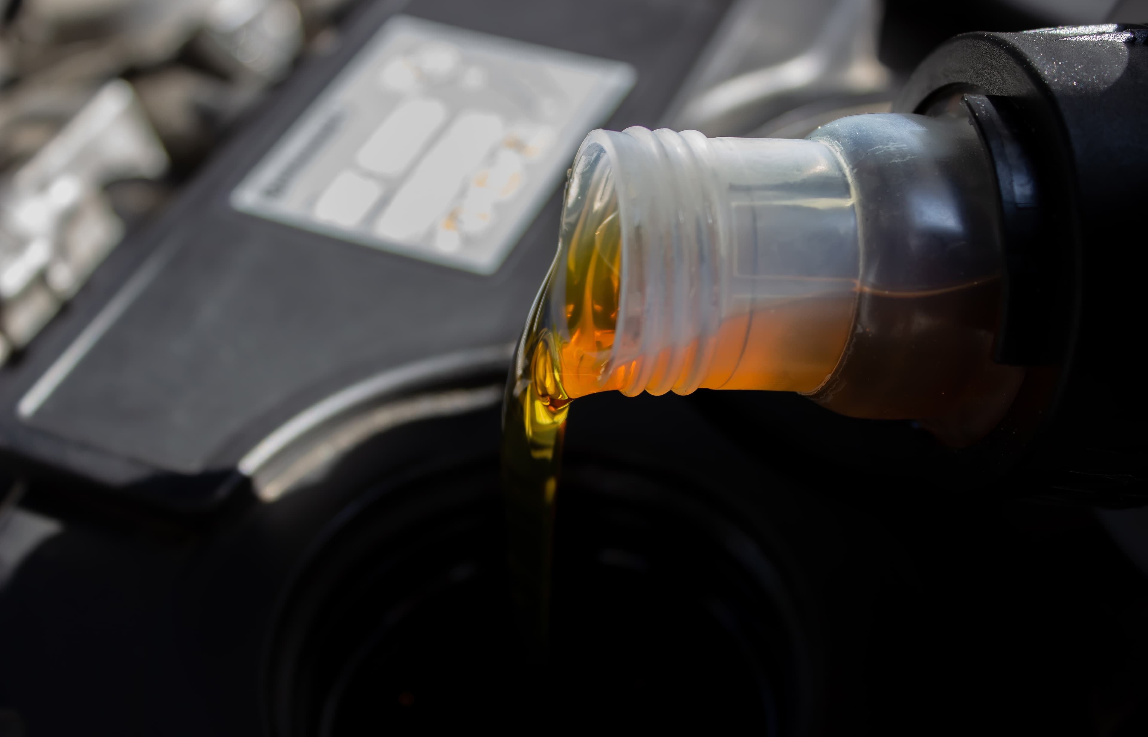 Close-up of engine oil being poured into the oil filler cap during car service