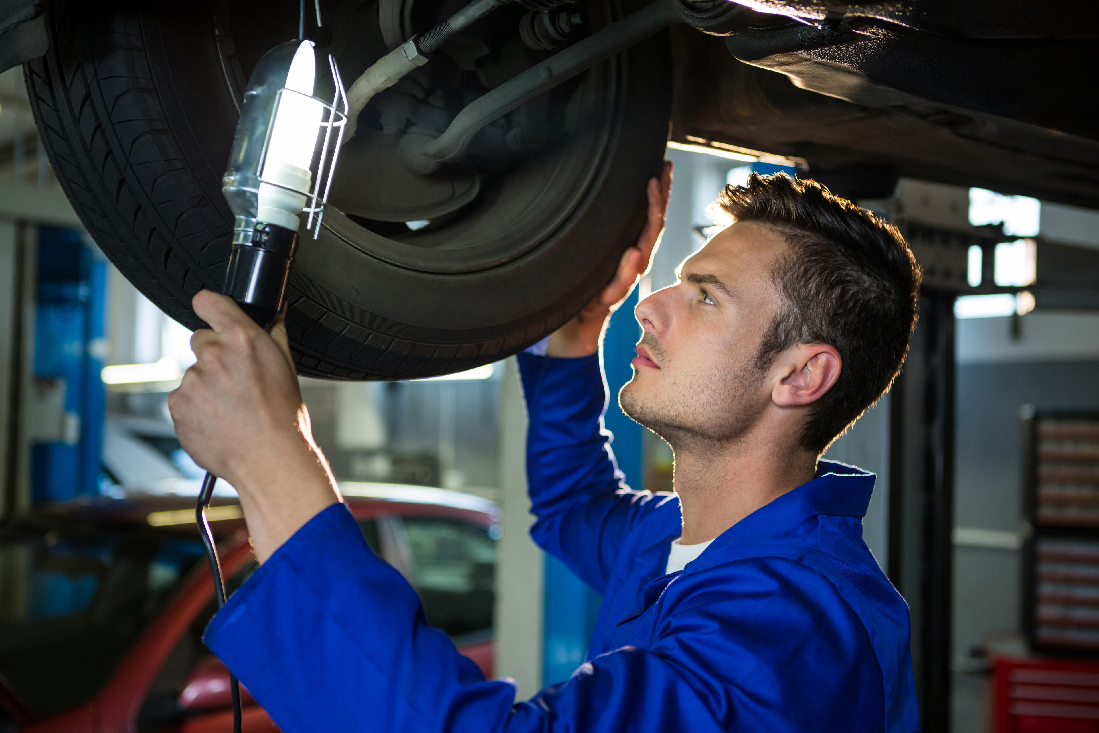 Technik wymieniający zużyte końcówki drążków kierowniczych